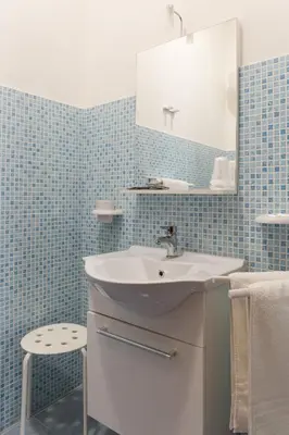 a bathroom with a sink and a mirror and a stool at Floreo Guest House in Rome