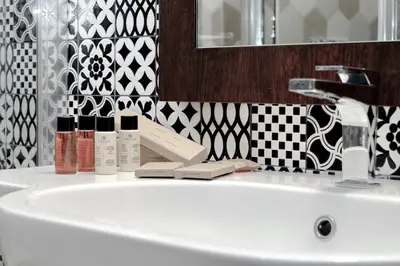 a white sink in a bathroom with black and white tiles at The Babuino - Luxury serviced apartment in Rome