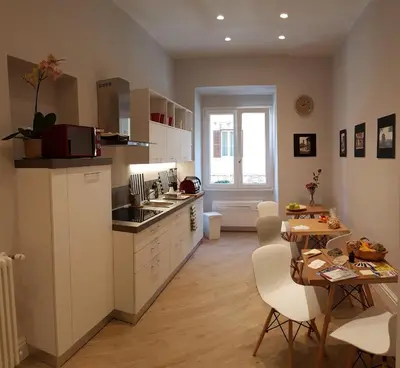 a kitchen with white cabinets and a table with chairs at Roman Suite Guest House in Rome