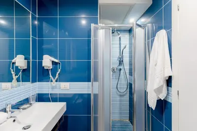 a blue tiled bathroom with a shower and a sink at Rhome Accomodation in Rome