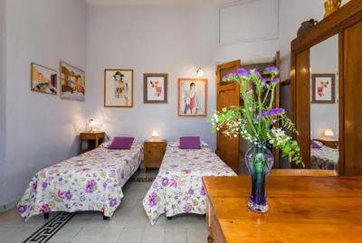 a room with two beds and a vase of flowers on a table at Colosseo Holiday House in Rome
