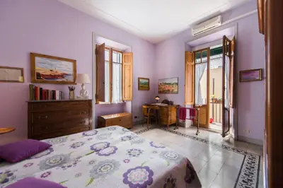 a bedroom with a bed and a dresser and windows at Colosseo Holiday House in Rome