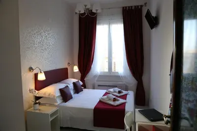 a bedroom with a bed and a window with red curtains at FHR-Appartamento a San Giovanni in Rome