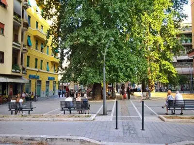a group of people sitting on benches on a city street at FHR-Appartamento a San Giovanni in Rome