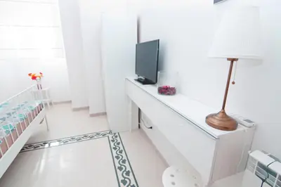 a white room with a tv and a desk with a lamp at Mio House Vatican in Rome