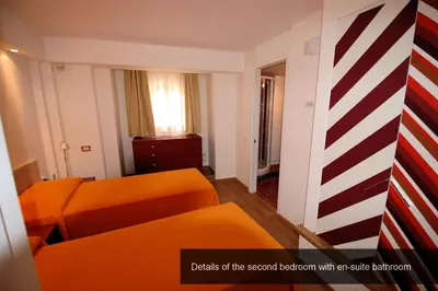 a living room with an orange couch and a striped room at HISTORICAL CENTER ROME NAVONA AC 2 ROOMS HOLY DOOR VATICAN 5 MINUTES ON WALk in Rome