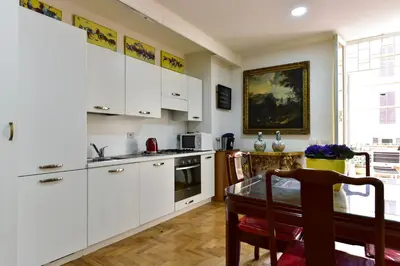 a kitchen with white cabinets and a dining table at Elite Rome Apartments in Rome