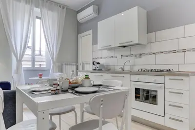 a white kitchen with a table and chairs at Appartamento Santi Quattro - Colosseo in Rome