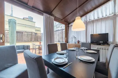 a dining room with a table and chairs and a television at Vatican Luxury Terrace in Rome