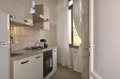 a kitchen with white cabinets and a stove and a window at Domus in Laterano in Rome