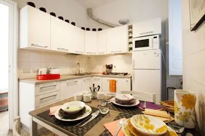 a kitchen with white cabinets and a table with dishes on it at Wanderlust - FromHometoRome in Rome