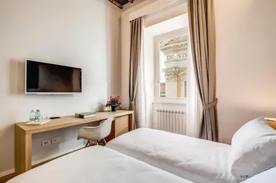 a hotel room with two beds and a desk at Dopodomani Suite in Rome