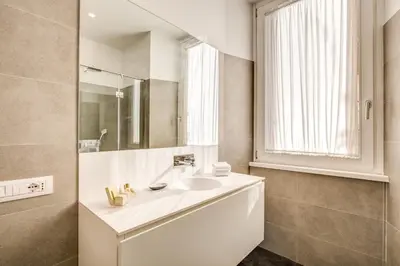 a white bathroom with a sink and a mirror at Dopodomani Suite in Rome