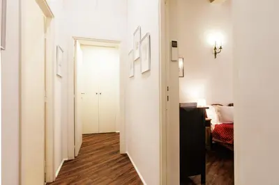 a hallway with white walls and wood floors and a bedroom at Vicolo Torretta - FromHometoRome in Rome