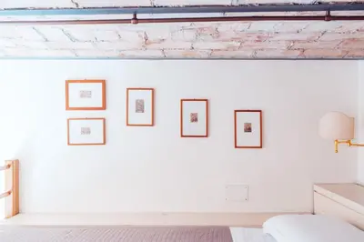 a white bedroom with four frames on the wall at Restart Accommodations Farnesina in Rome