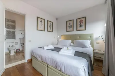 a bedroom with a large bed and a bathroom at Paradiso Penthouse - FromHometoRome in Rome