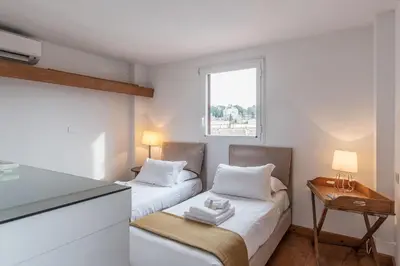 a small room with two beds and a window at Paradiso Penthouse - FromHometoRome in Rome