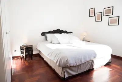 a bedroom with a large white bed with a wooden floor at Porta Latina Apartment in Rome