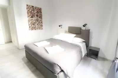 a white bedroom with a bed and a painting on the wall at CinqueSogni Guest House in Rome