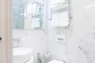 a white bathroom with a sink and a mirror at Margherita Suites in Rome