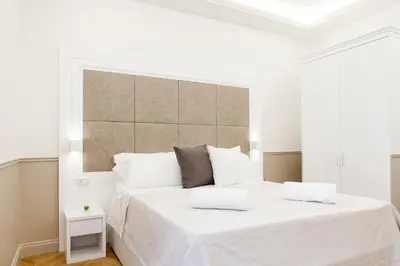 a white bedroom with a large bed with white sheets at Margherita Suites in Rome
