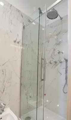 a shower with a glass door next to a sink at Margherita Suites in Rome