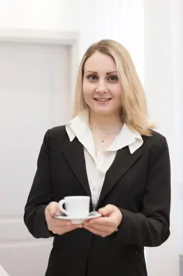 a woman in a suit holding a cup of coffee at Margherita Suites in Rome