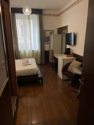 a hotel room with a bed and a desk and a chair at Gold House in Rome
