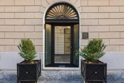two plants in black containers in front of a door at Navona Street Hotel in Rome