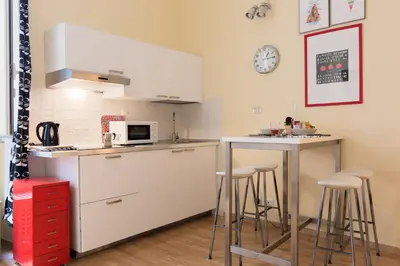 a kitchen with white cabinets and bar stools at Casa Vacanze Colosseum by Alice in Rome