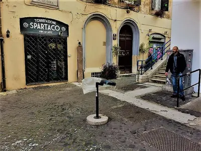 a man is standing in front of a building at Casa Vacanze Colosseum by Alice in Rome