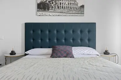 a bed with a blue tufted headboard and a pillow at Sapienza Apartment by RHR in Rome
