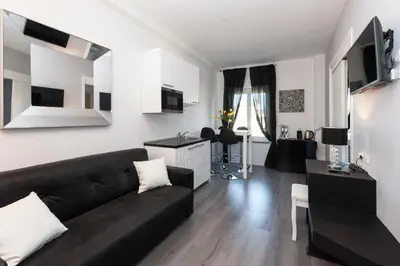 a living room with a black couch and a kitchen at Brunelleschi Holidays Hostel in Rome