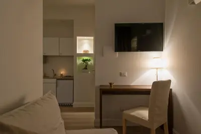 a living room with a table with a lamp and a kitchen at Aruna Suites in Rome