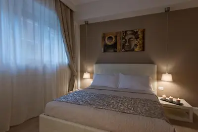 a bedroom with a bed with a portrait on the wall at Aruna Suites in Rome