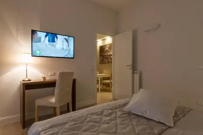 a bedroom with a bed and a desk and a television on the wall at Aruna Suites in Rome