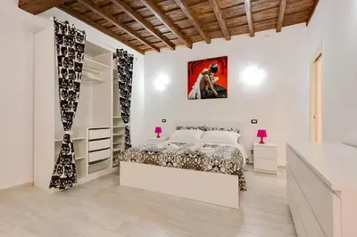 a white bedroom with a bed and a mirror at Casa Vacanze Colosseum by Serena in Rome