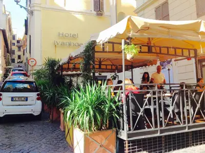 a restaurant with people sitting under an umbrella on a street at Casa Vacanze Colosseum by Serena in Rome