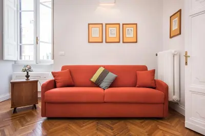 an orange couch in a living room with a table at Casa Minerva Al Pantheon in Rome