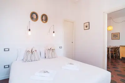 a white bedroom with a white bed and a table at HC - Sunny Apartment in Testaccio! in Rome