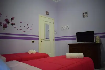 a bedroom with two red beds and a tv at I Petali Guest House in Rome