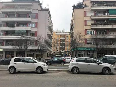 three white cars parked in a parking lot with buildings at Vatican City House Roma in Rome