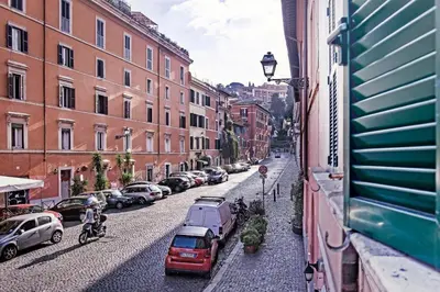 a city street with cars and a person riding a bike at TrastevereHome - Garibaldi Rome in Rome