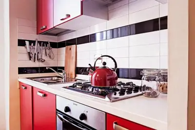 a red tea kettle sitting on a stove in a kitchen at TrastevereHome - Garibaldi Rome in Rome