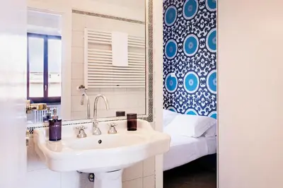 a bathroom with a sink and a mirror and a bed at TrastevereHome - Secret Calisto Amazing View Trastevere Rooftops in Rome