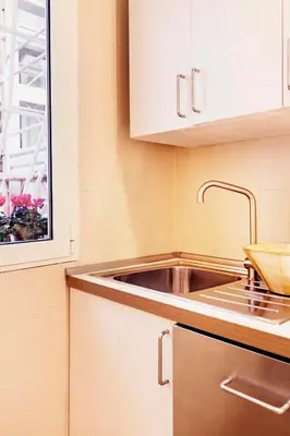 a kitchen with a sink and white cabinets at TrastevereHome - Paglia House of 17Century in Trastevere in Rome