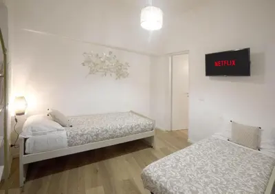 a bedroom with two beds and a tv on the wall at Buongiorno Colosseo in Rome
