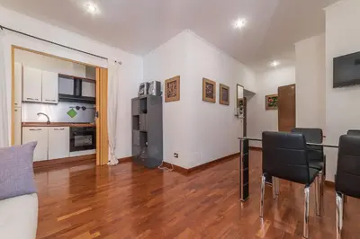a living room with a table and chairs and a kitchen at Casa Zeffiro - FromHometoRome in Rome