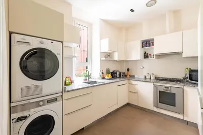 a kitchen with white cabinets and a washer and dryer at Popologrande Apartment in Rome