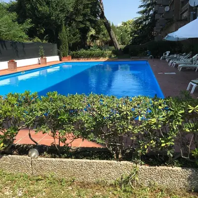 a large swimming pool with blue water in a yard at Megi San Peter Apartment in Rome